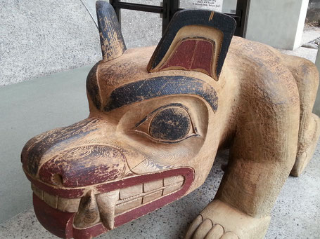 Un énorme chien avec deux canines menaçantes sculpté dans un tronc en bois massif, des touches de peinture rouges et noires le rendent plus agressif. #provence #art #ayniart.