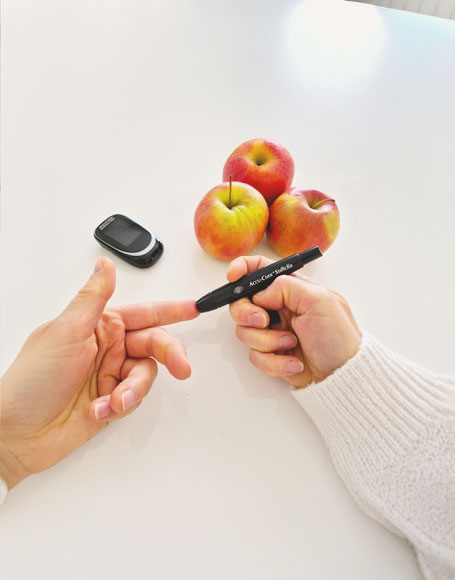 Jemand sticht sich mit einem Zuckermessgerät in den Finger. 