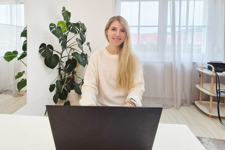 Julia Emberger sitzt vor dem Laptop und lächelt