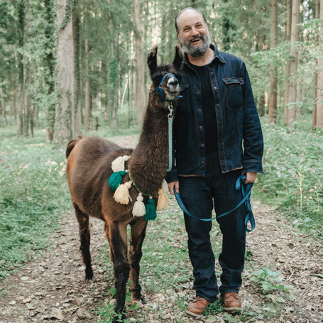 Lachender Mann hält ein Lama beim Teambuilding am Pointnerhof