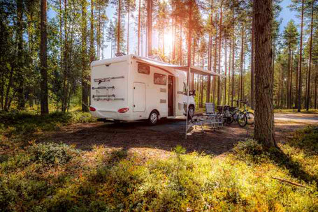 Weißes großes Wohnmobil campt im Wald in DeutschlandMann sitzt am Steuer vom Auto und dreht den Zündschlüssel 2026