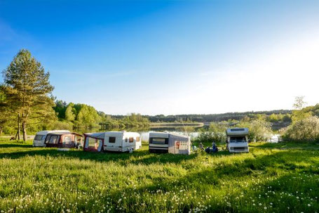 Wohnwagen auf einer Wiese am See in der Sonne 2026