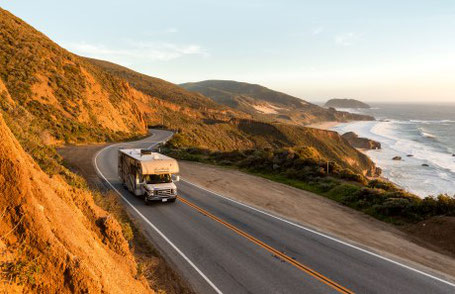 Alkoven Wohnmobil an einer bergigen US Küstenstraße bei Sonnenuntergang 2025
