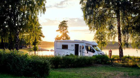 Wohnmobil steht an einem See im Sonnenuntergang 2026