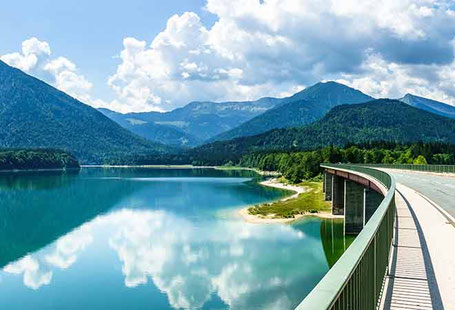 Brücke über blauen Bergsee mit Bergpanorama 2026