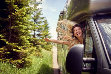 Frau hält Kopf aus dem Fenster von Wohnmobil mit wehenden Haaren 2026