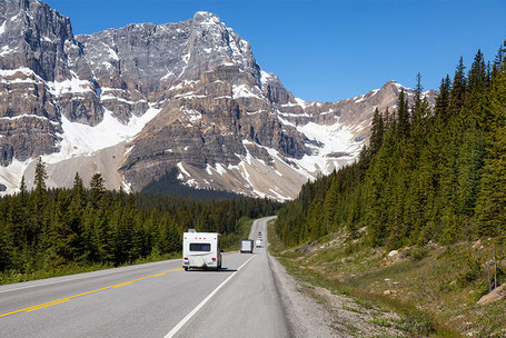 Weißes Wohnmobil auf Straße in den Bergen neben Wald in Kanada 2026
