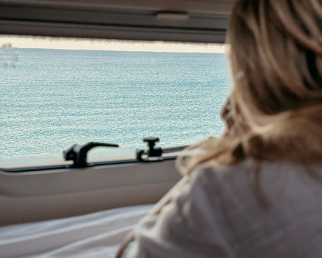 Frau guckt aus Camper Van auf Meer Fuerteventura