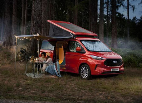 Roter Ford Nugget mit Markise im Wald 2025