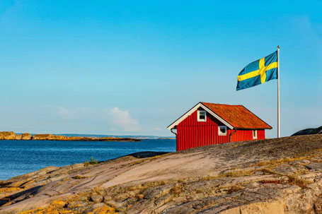 Schwedenhaus am Meer mit Flagge auf einem Felsen 2026