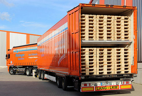 Ein Doppelstock-Lkw-Anhänger hängt an der Zugmaschine: Es ist ein Lang-Lkw. Man blickt auf die hintere offene Seite: Auf 2 Ebenen sind viele neue Paletten aufgeladen.