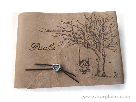Fotoalbum, individuelle Brandmalerei von Hand: Baum, Mädchen auf Schaukel, Name, Geburtsdatum; Bucheinbandmaterial Spaltleder natur, Softcover mit Überschlag, kurzer Buchverschluss Herzknopf, Querformat 35cm x 25cm, 50 Blatt mit Pergaminzwischenblättern.