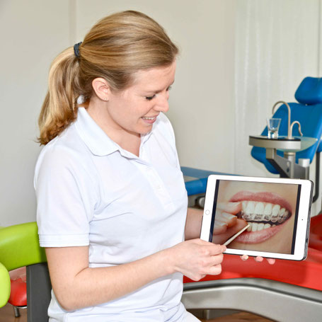 Kieferorthopädin in Gröbenzell, Dr. Gerth, erklärt am iPad die Therapie mit unsichtbaren Invisalign Zahnschienen.