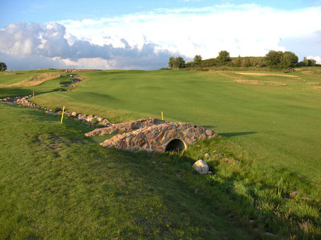 Golfplatz mit alter kleiner Steinbrücke im Vordergrund