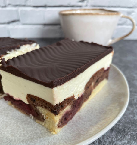 Ein Stück Donauwelle auf einem Teller und im Hintergrund eine Tasse Kaffee