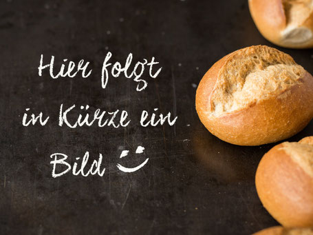 Ein angebissenes Küster-Brötchen mit dicken Stracke-Scheiben liegt auf Backpapier