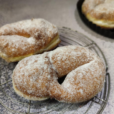 Zwei zuckrige Krapfen liegen auf einem Kuchengitter