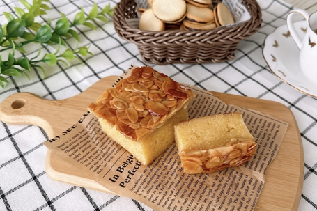 カッティングボードにアーモンドがのった焼き菓子。チョコレートがサンドされたクッキーが盛り付けられたかご。