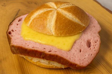 Leberkässemmel mit geschmolzenem Käse und Kraut, rustikal angerichtet im natürlichen Licht