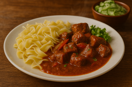 Alt-Text: „Gulasch mit Nudeln und Gurkensalat, rustikal angerichtet im natürlichen Licht“