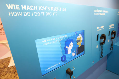 Draufsicht auf blauen Kobus "Wie mache ich es richtig" Auf der linken Seite zwei Comicfiguren, rechts zwei Telefonhörern