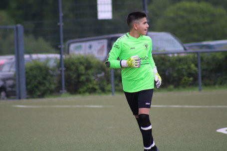 Junger Torwart im grünen Trikot und mit Torwarthandschuhen