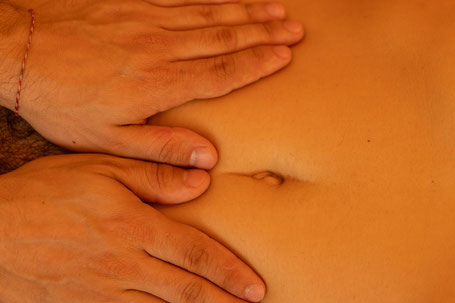 Eine Nahaufnahme, die zeigt, wie die Hände eines Masseurs sanft den Bauch einer Person massieren