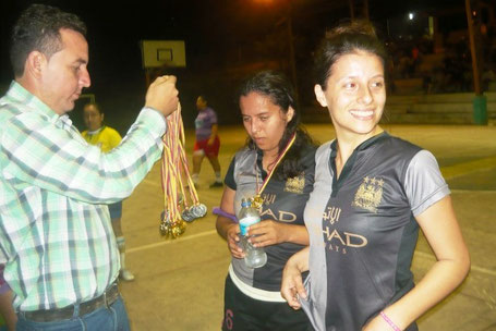 El presidente de la Asociación de Estudiantes de la Uleam, Javier Chumo, premia a dos ciclistas que ganaron prueba en agosto. El Carmen, Ecuador.
