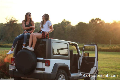 Deux jeunes femmes installées sur le hard-top d'un Wrangler et au dessus d'une housse roue de secours Jeep