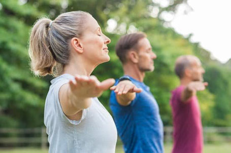 Pratique du qi gong en plein air par trois adultes européens.