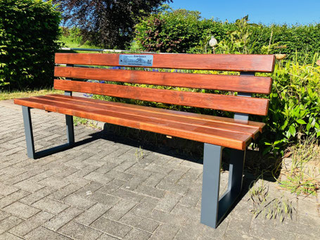 Bank zum Sitzen mit Metallgestell und Sitzfläche und Lehne aus Holz.