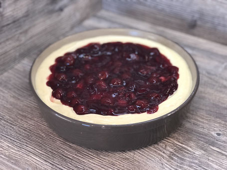 Runde Springform aus Ton in der Farbe grau, mit Käsekuchen und Kirschen befüllt