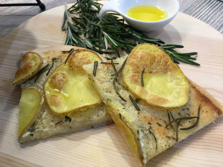 Kartoffel-Rosmarin-Pizza fertig angerichtet auf Holtplatte mit Rosmarin und Olivenöl-Schälchen
