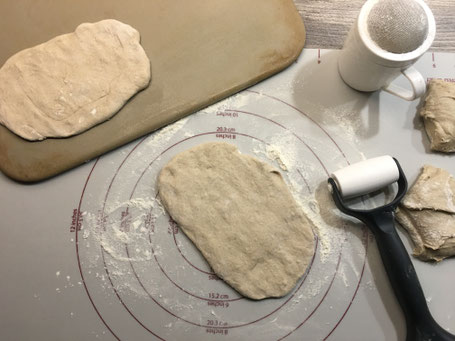 Backmatte mit Teig der zu kleinen Fladen ausgerollt wird.