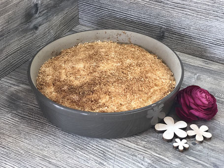 Springform in rund aus Ton in der Farbe grau mit Kuchenteig gefüllt. Fertig gebacken