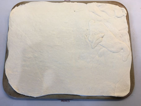 Ausgerollter Pizzateig auf dem Tonbackstein von Pampered Chef