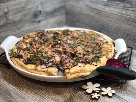 Runde weißer Stoneware-Form auf Arbeitspalatte mit Fett bestrichen, Pizzateig belegt und Zwiebeln und Käse belegt, fertig gebacken