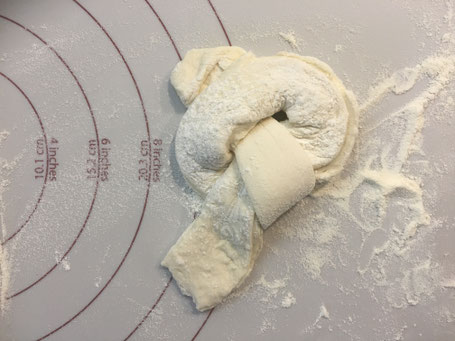 Brötchenteig auf einer Teigunterlage liegend.