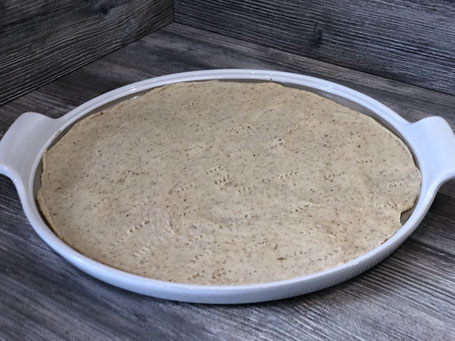 Flache Backform der Firma Pampered Chef, rund und weiß, mit Kuchenteig belegt