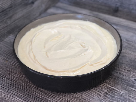 Runde Springform aus Ton in der Farbe grau, mit Käsekuchen-Teig gefüllt