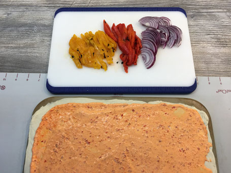 Pizzateig ausgerollt mit Sause bestrichen auf dem Tonstein von Pampered Chef.