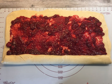 Brioche-Teig ausgerollt auf Backmatte und mit Himbeer-Füllung bestrichen