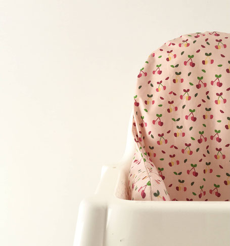 cette image représente un coussin de chaise haute en coton enduit avec de petites cerises comme motif