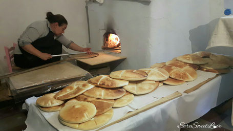 donna orgolese che inforna il pane tipico nel forno a legna