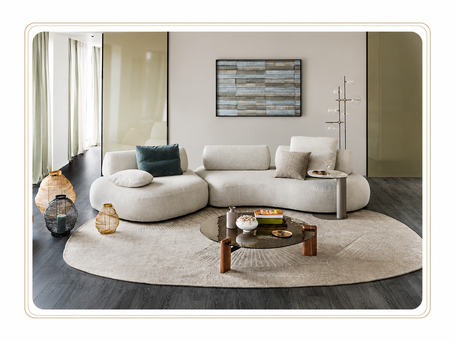 Divano moderno in tessuto chiaro con poltrone, tavolino e tappeto in una zona living elegante e contemporanea.