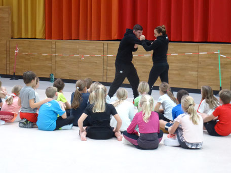 Die Trainer zeigen den Kindern einen Abwehrhandgriff