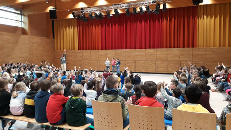 Alle Schülerinnen und Schüler versammeln sich in der Halle zur Schülerversammlung