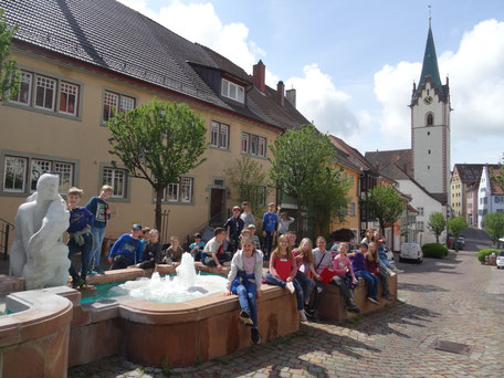 Die Klasse 3c sitzt auf dem Brunnen vor der Stadtkirche Mariä Himmelfahrt