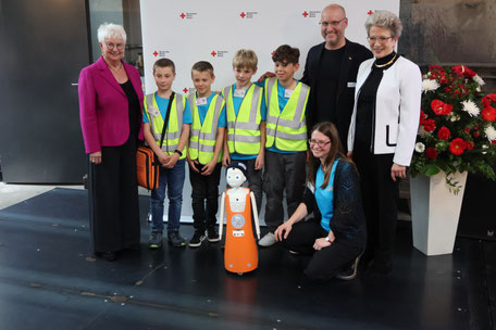 Eine Delegation Juniorhelfer mit den Präsidentinnen Bosch und Hasselfeldt des DRK, sowie Navel einer künstlichen Intelligenz