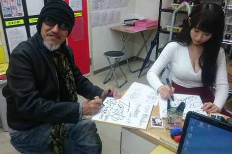 事務所でサインを書いてくれてるトージロー監督と美咲結衣さん。
